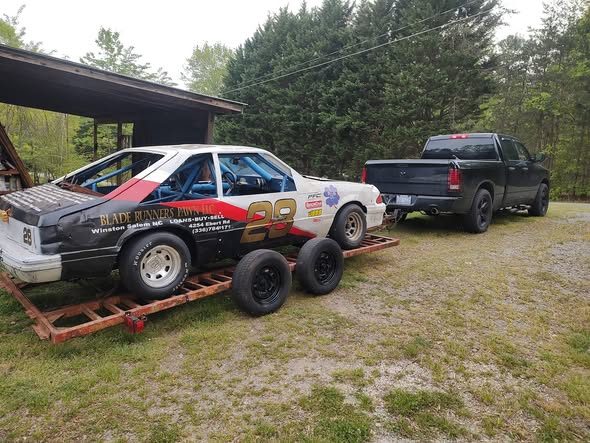 The #28 loaded on an open trailer behind a black pickup